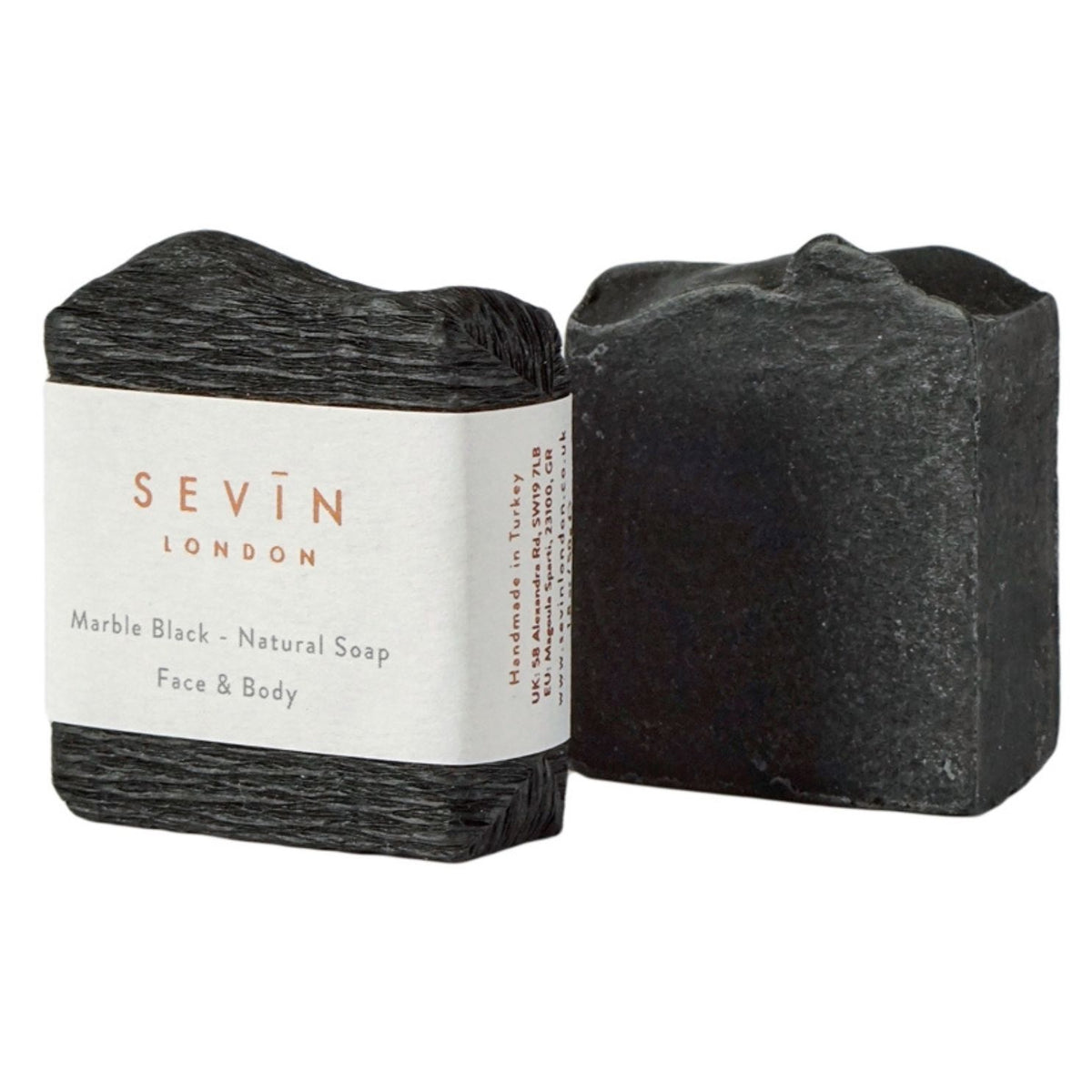 Two bars of Sevín London Marble Black natural soap, one wrapped in a white paper band and one unwrapped, showing a dark charcoal gray stone texture, on a plain white background.